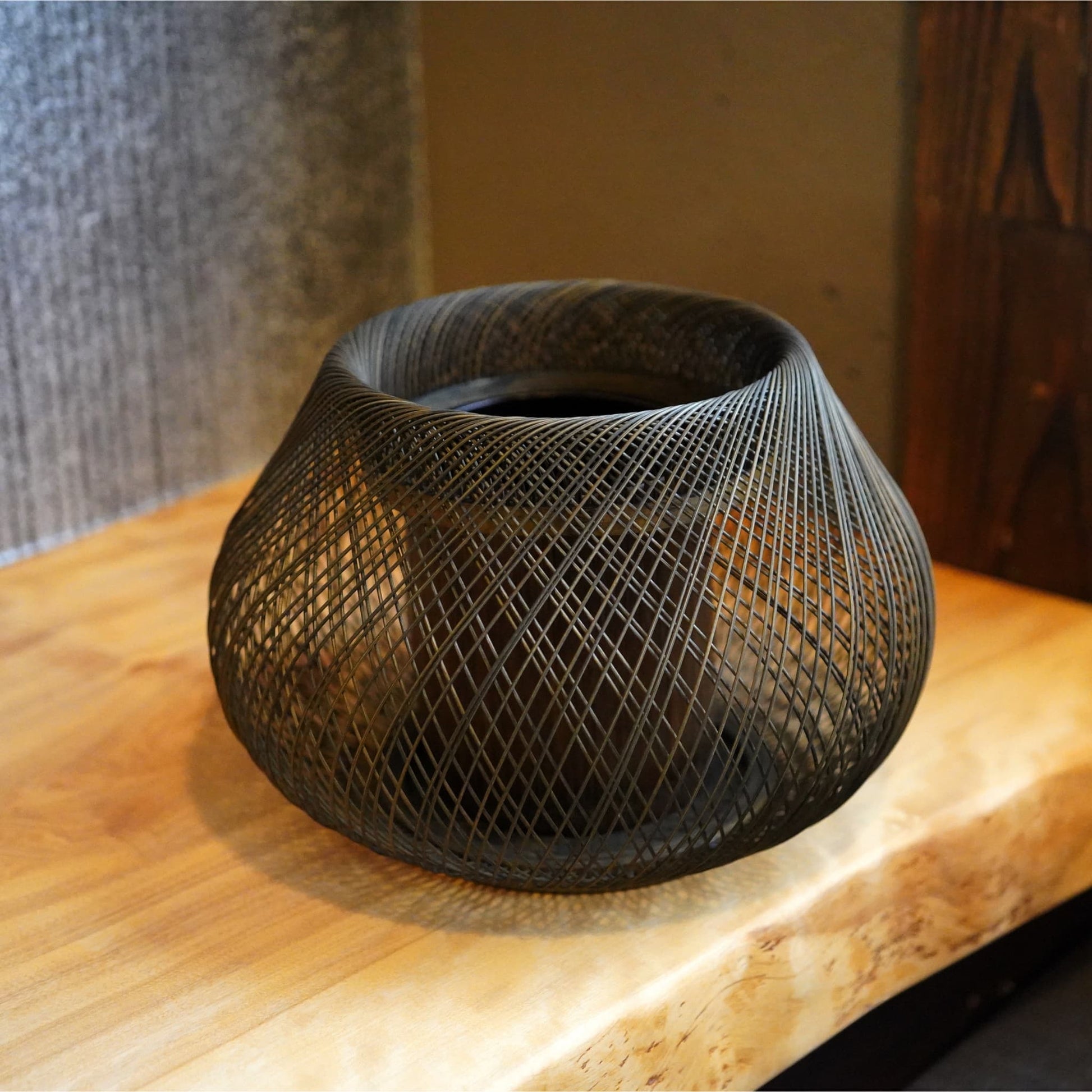 An oval-shaped Japanese ikebana vase resting on a wooden Japanese-style table.