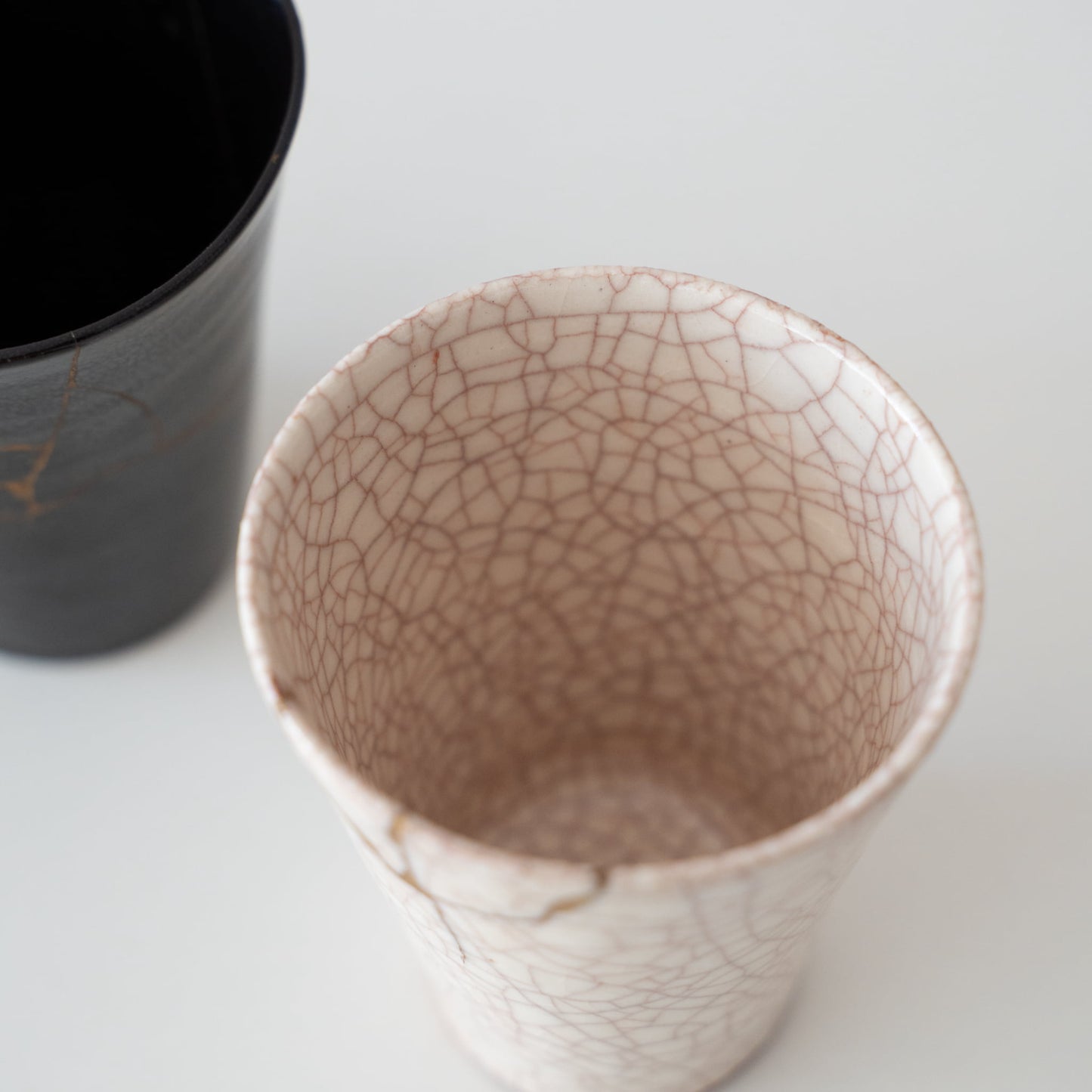 White ceramic cup repaired with kintsugi, a traditional Japanese art of mending broken pottery with gold lacquer