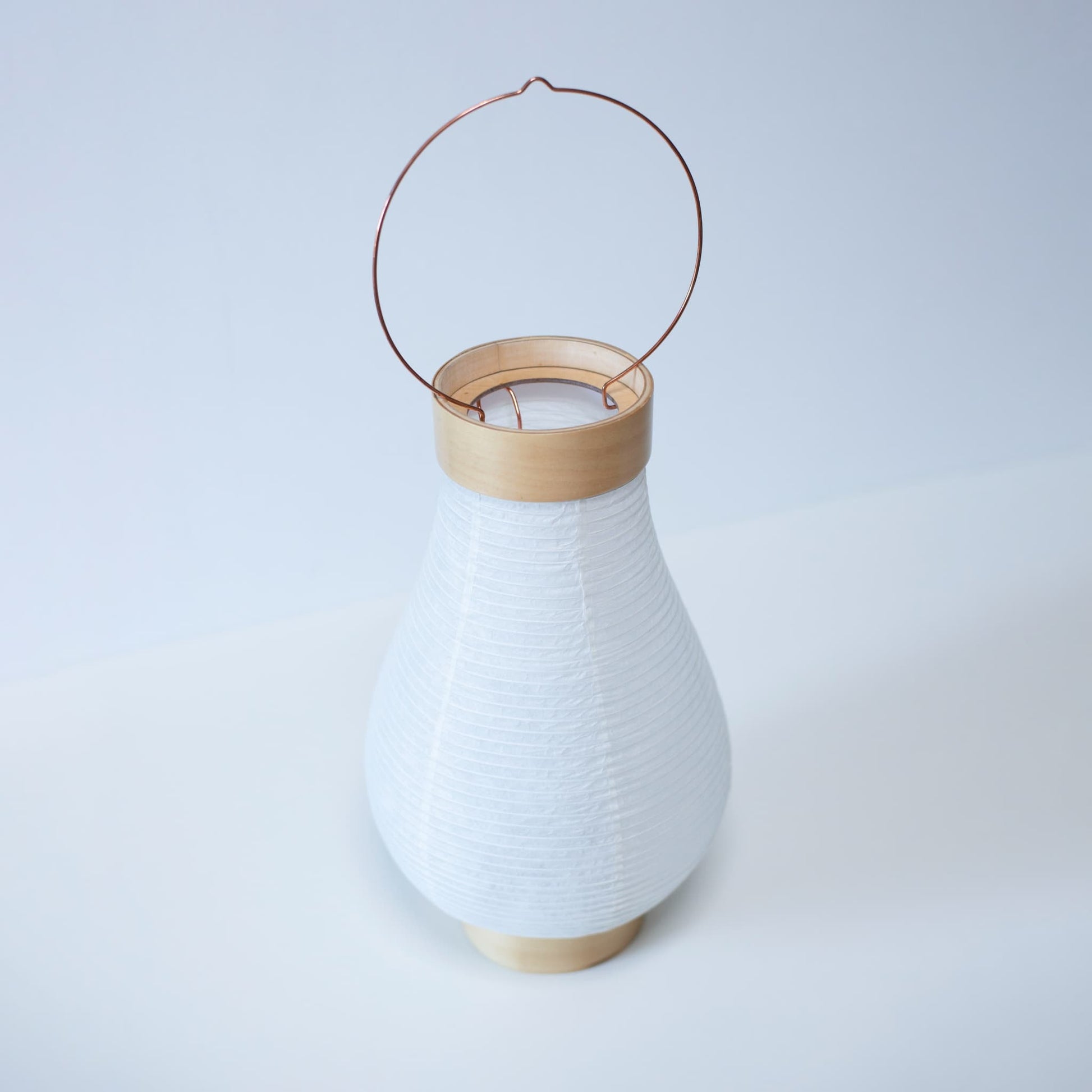 A traditional Japanese paper lantern photographed from above against bright white wallpaper