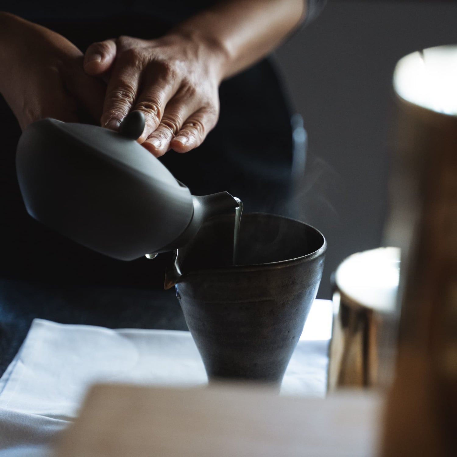 Tea is being poured from a black teapot.