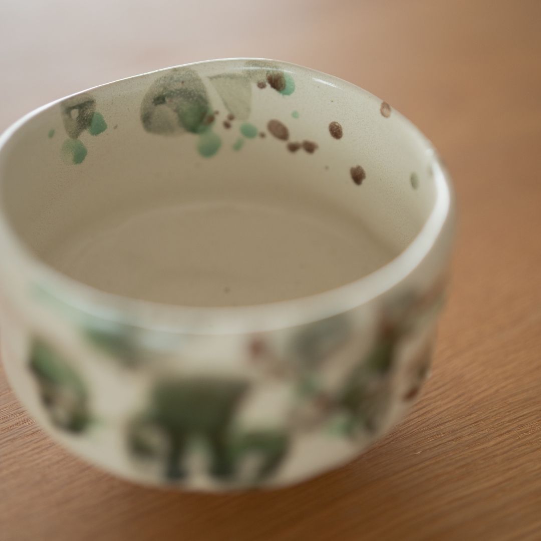 High-angle view into the "Forest" matcha bowl, showing the creamy white base speckled with green artisan glaze, creating a serene tea ceremony experience.