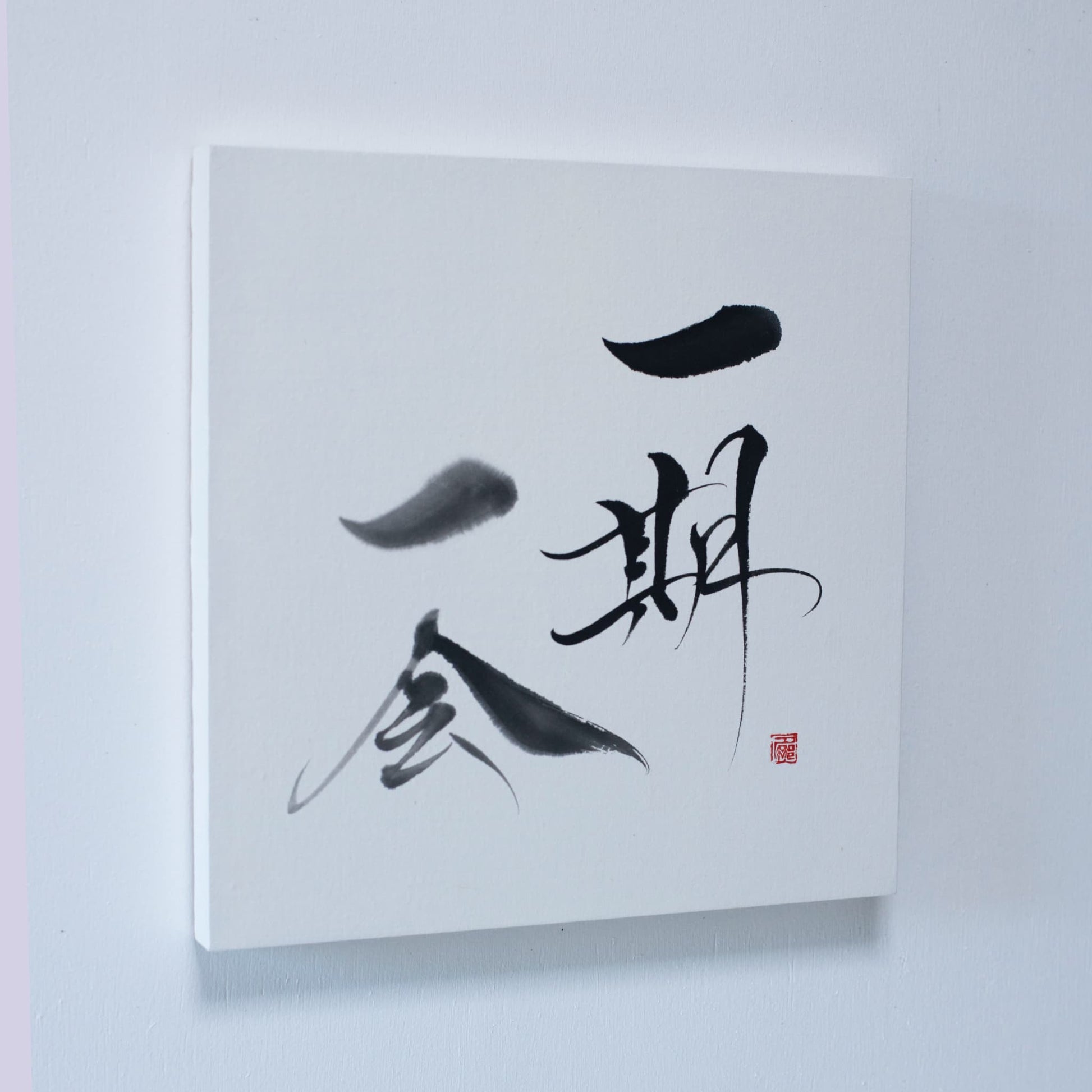 A panel displaying 'Ichigo Ichie' in Japanese calligraphy, mounted on a white wall. 
