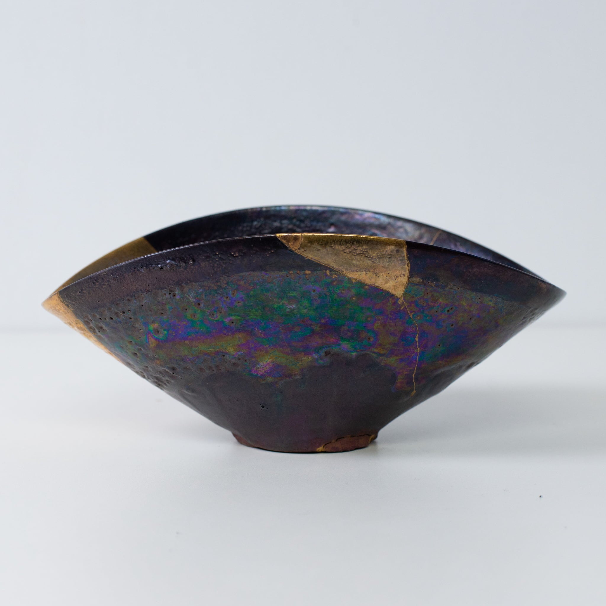 Side profile of Kintsugi pottery bowl with iridescent glaze and gold kintsugi seams