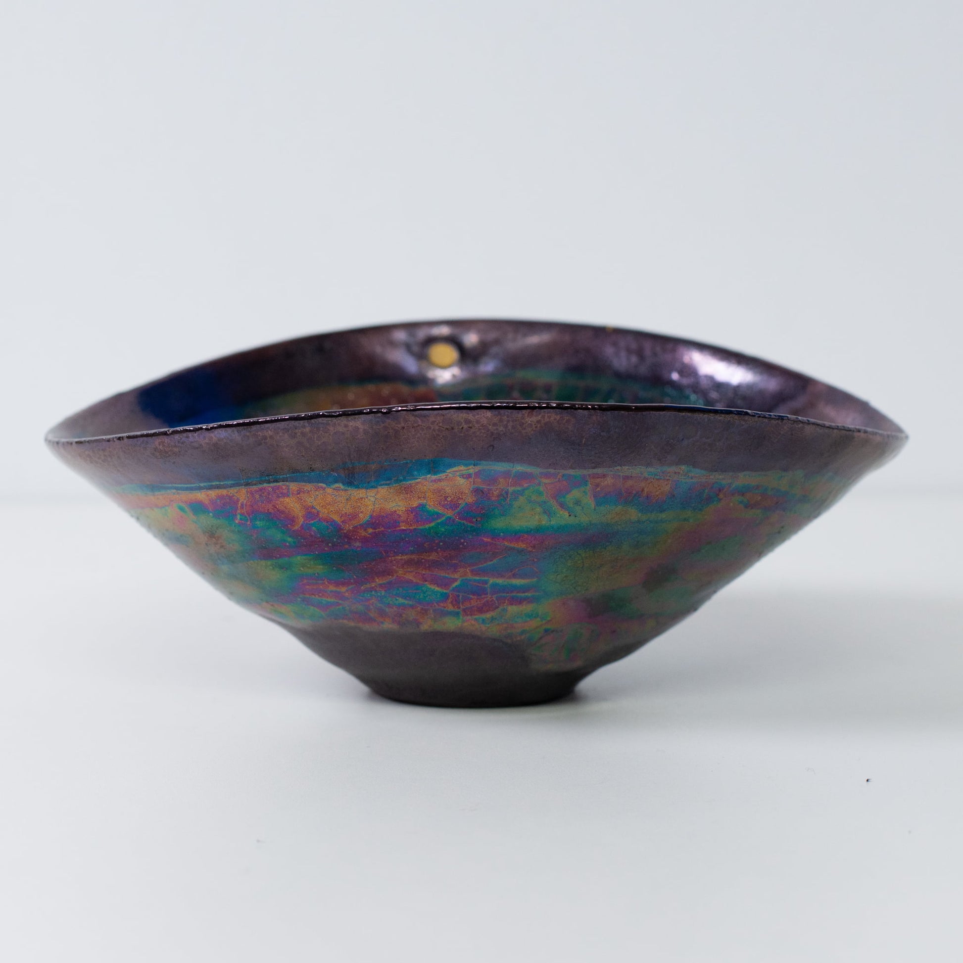 Japanese Kintsugi pottery bowl side view with metallic glaze and gold-filled cracks