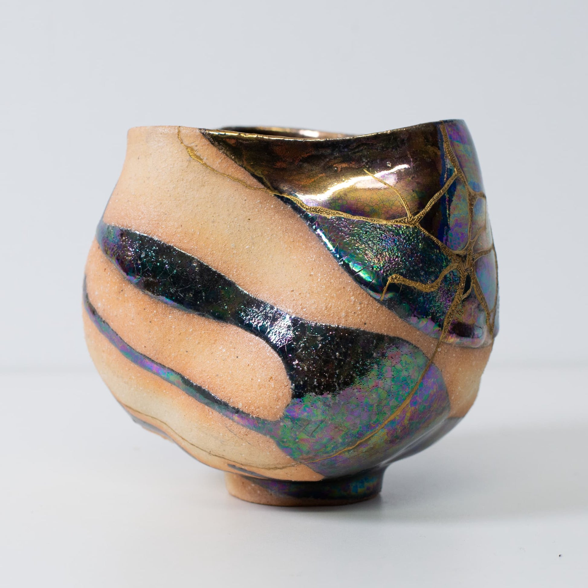 Side view of kintsugi pottery matcha bowl with golden seams and natural wabi-sabi form