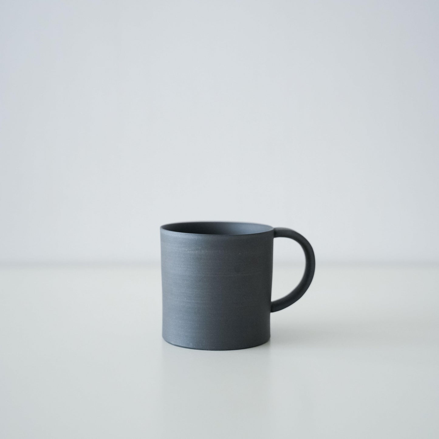 A simple black mug made of traditional Banko ware.