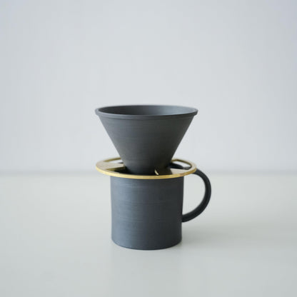 A minimalist black coffee mug and coffee dripper