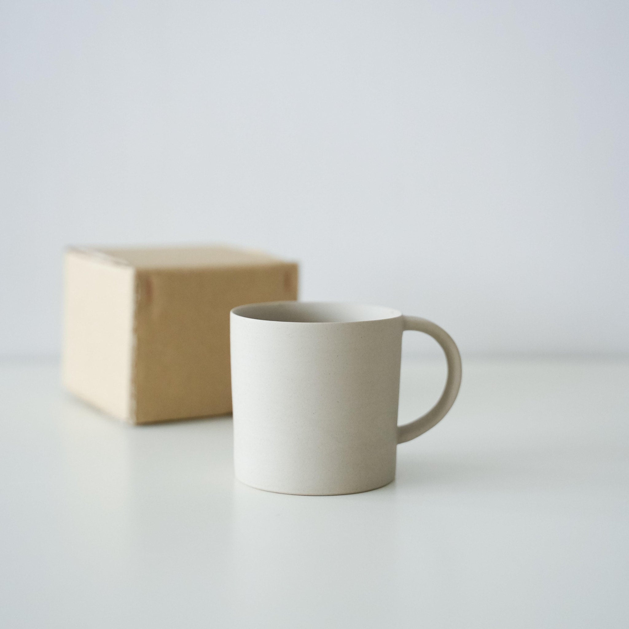 A simple white Banko ware mug in a minimalist paper box.