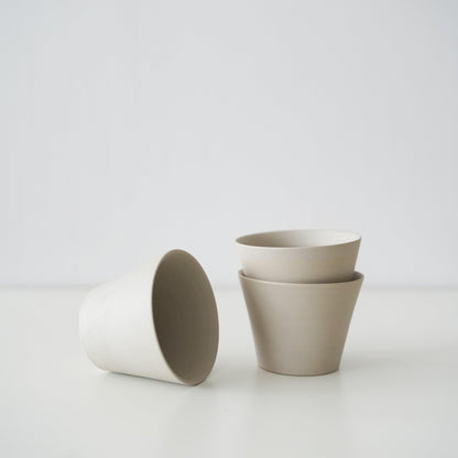 Two minimalist white conical teacups from Banko ware stacked together.