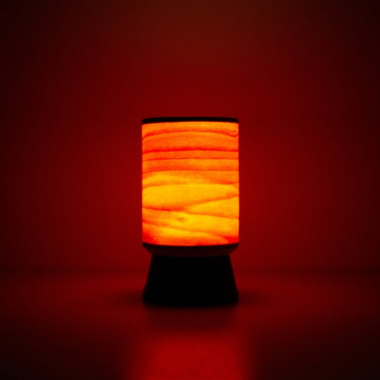 Japanese wood light lamp with warm reddish glow through beech shade, perfect for cozy interiors.