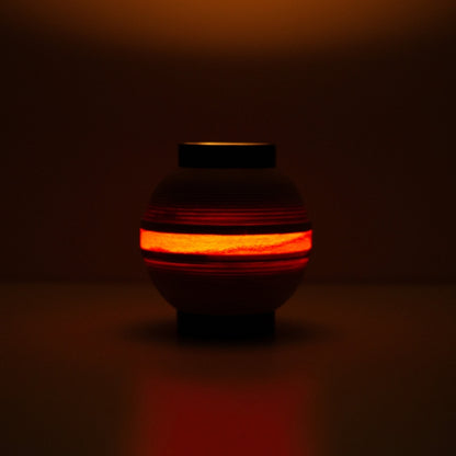 Japanese table lamp with glowing ring of light, casting a flame-like hue for ambient interiors.