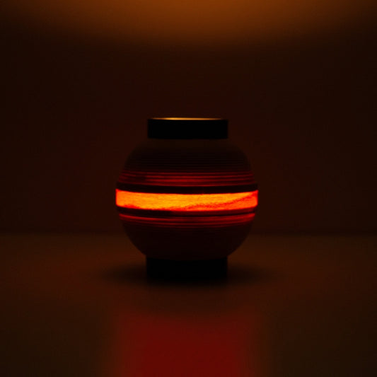 Japanese table lamp with glowing ring of light, casting a flame-like hue for ambient interiors.