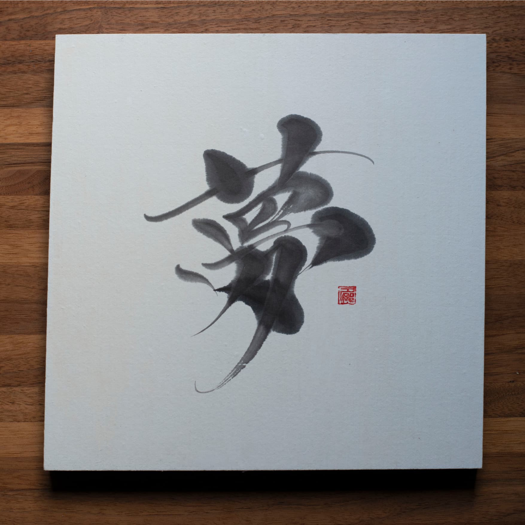 A top-down photo of a square panel with the Japanese character for "dream" (夢) written in calligraphy, placed on a wooden table.