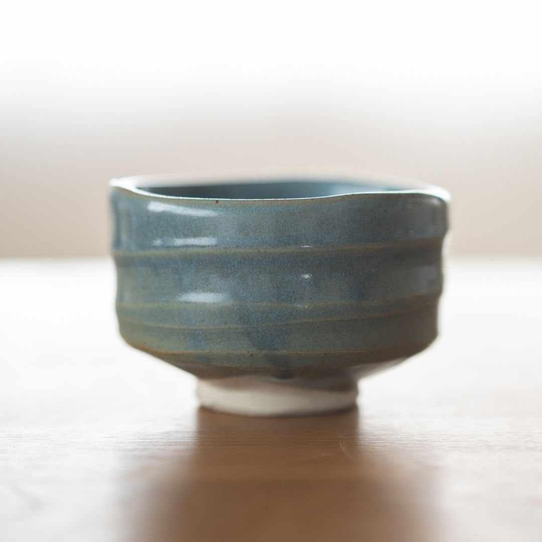 Centered shot of the handmade "Summer Sky" matcha chawan from Shinzan Kiln, featuring the irregular, organic rim and visible white clay base, emphasizing its Japanese ceramic artistry.
