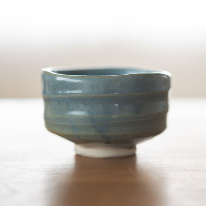 Centered shot of the handmade "Summer Sky" matcha chawan from Shinzan Kiln, featuring the irregular, organic rim and visible white clay base, emphasizing its Japanese ceramic artistry.