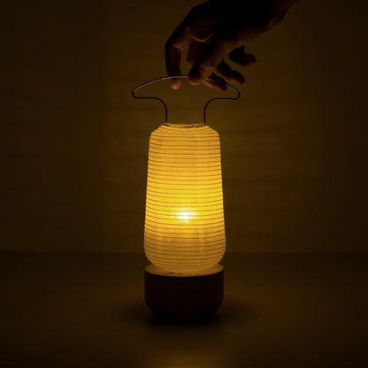 A warm-glowing traditional Japanese paper lantern in a dark room