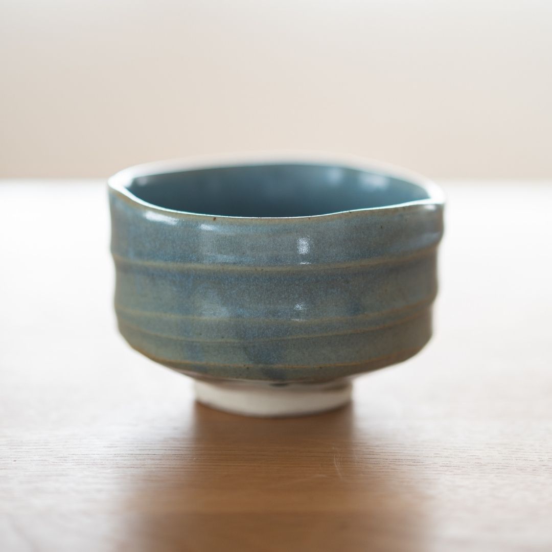 Detailed view of the "Summer Sky" Japanese matcha bowl's exterior, focusing on the rough, wabi sabi ceramic texture and how the blue glaze thins over the clay ridges.