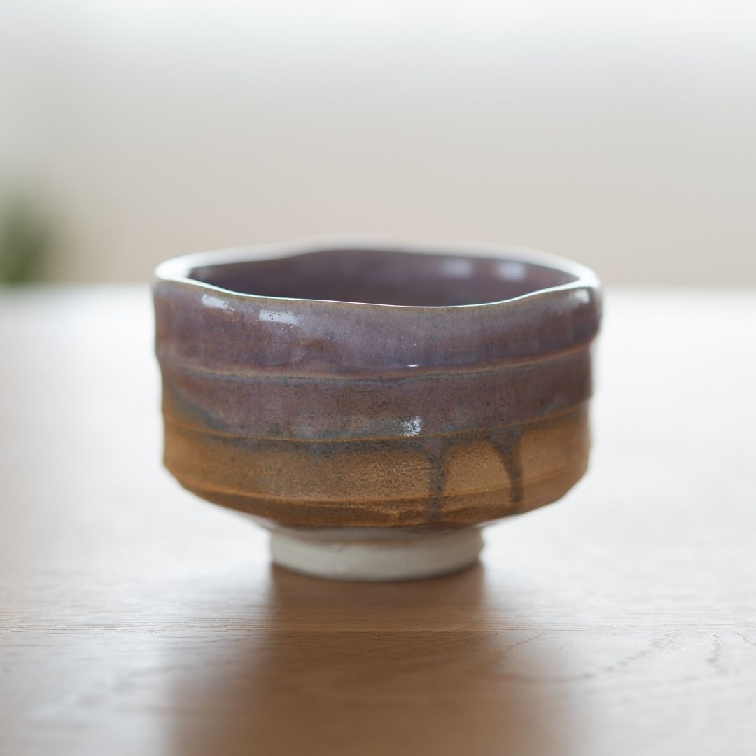 Full view of the wabi sabi style Japanese matcha chawan in Pale Violet Haze, featuring a natural gradient violet glaze over textured earth tones.