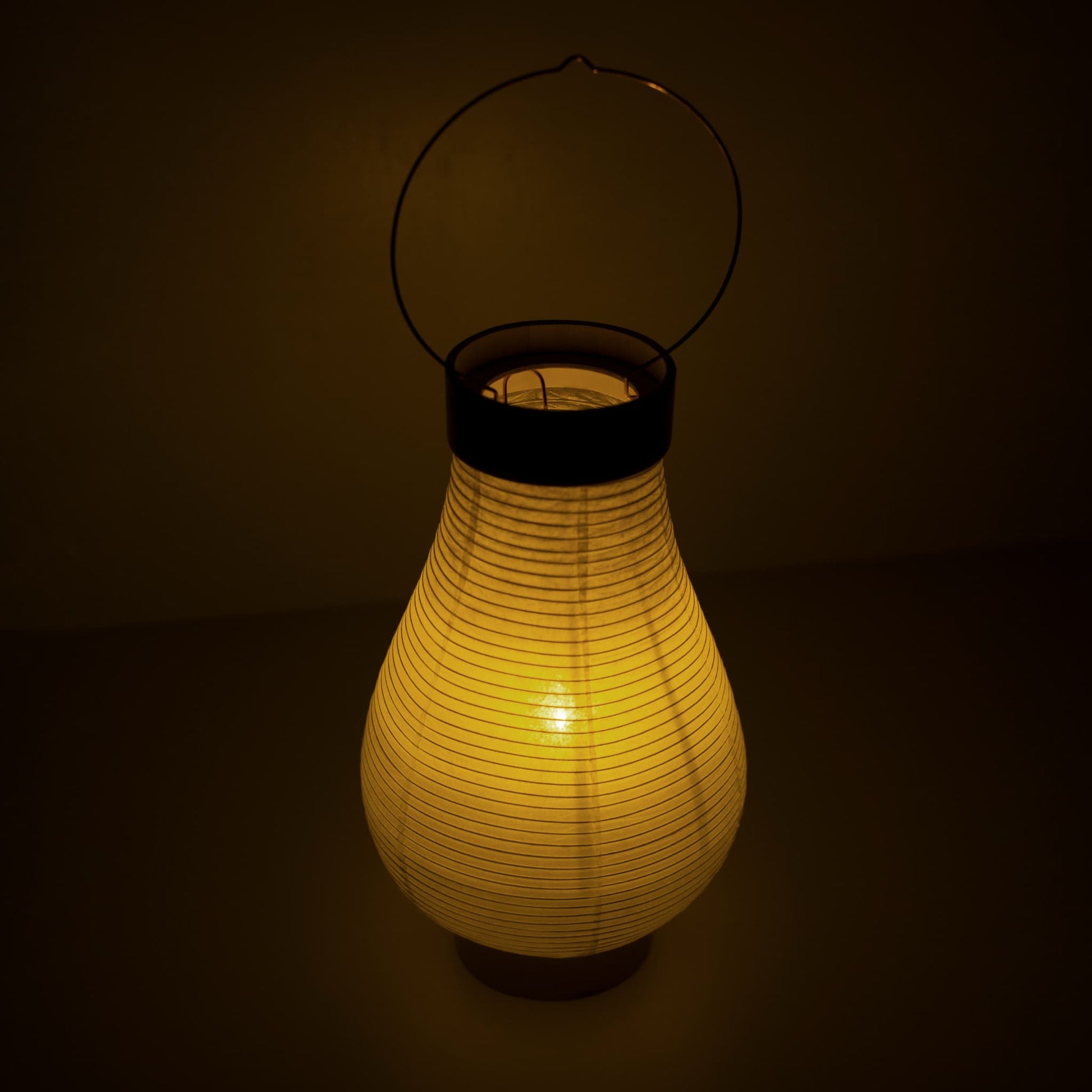 A traditional Japanese paper lantern with warm lighting in a dim room