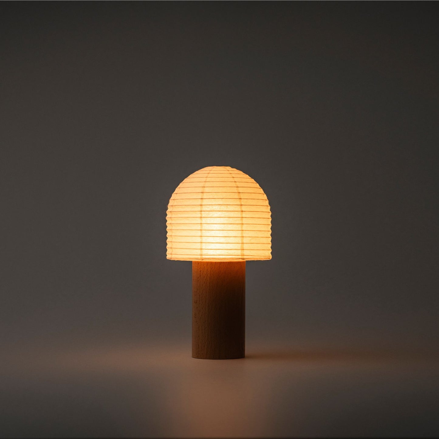 A Yame lantern with a bell-shaped top and wooden handle, emitting bright warm light in a dark room