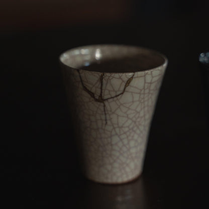 White ceramic cup repaired with kintsugi, a traditional Japanese art of mending broken pottery with gold lacquer, showcasing the beauty of imperfection and embracing the concept of wabi-sabi.