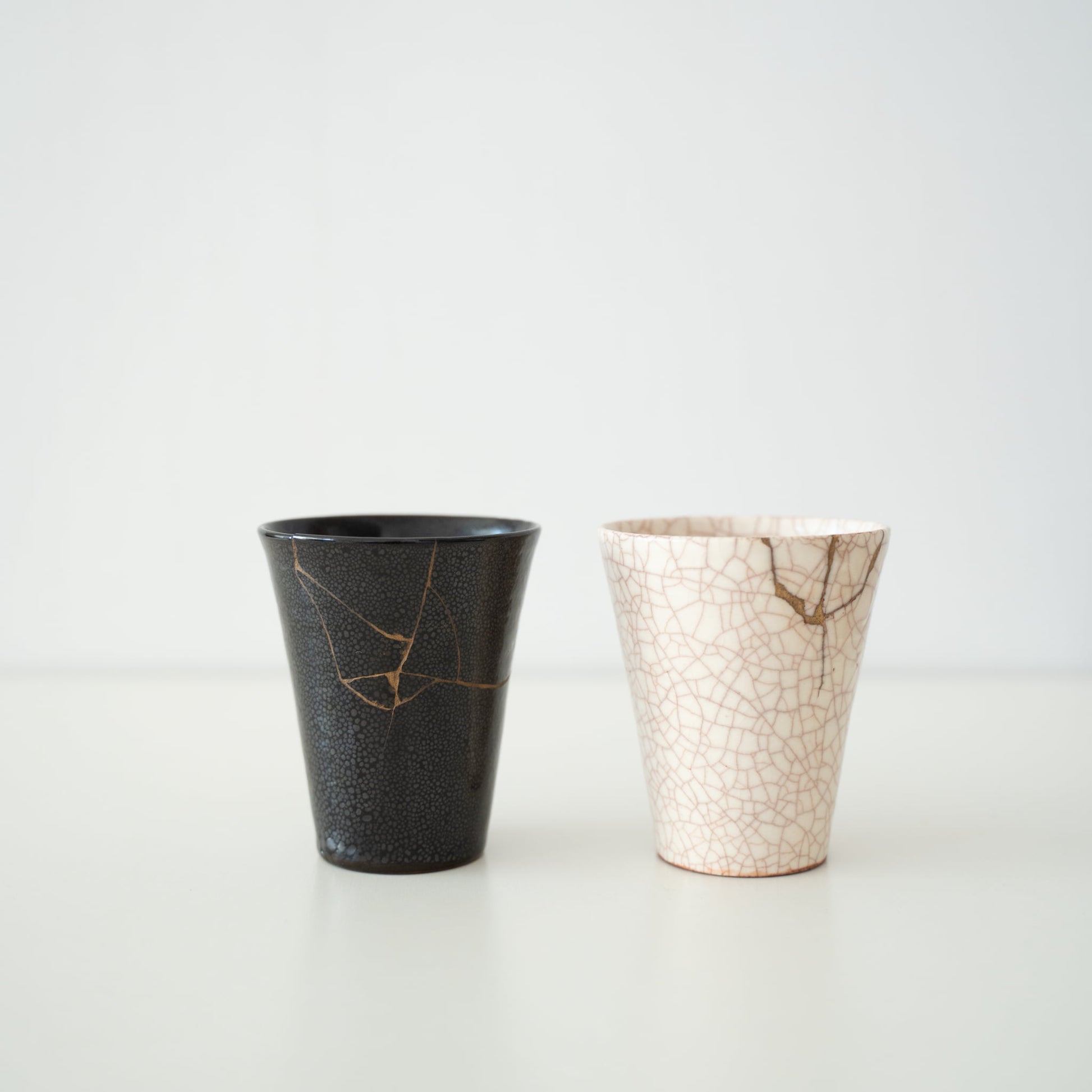 White and black ceramic cup repaired with kintsugi, a traditional Japanese art of mending broken pottery with gold lacquer, showcasing the beauty of imperfection and embracing the concept of wabi-sabi.