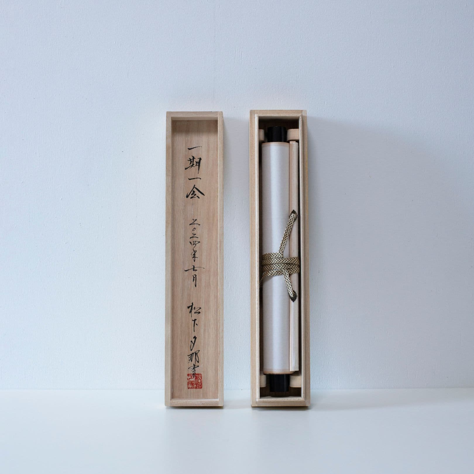 Wooden storage box and lid for a traditional Japanese hanging scroll, showing the scroll rolled up inside