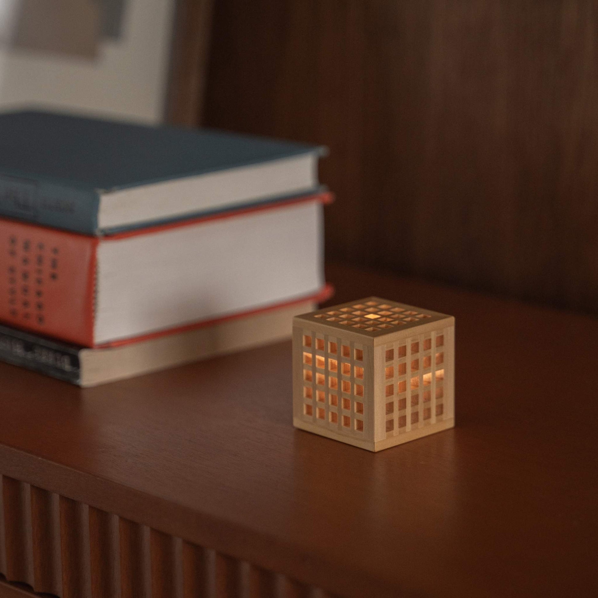 "Lampe japonaise en bois « Hotaru » projetant une lumière chaude à côté de livres, comme lampe de table sans fil et lampe d'appoint."