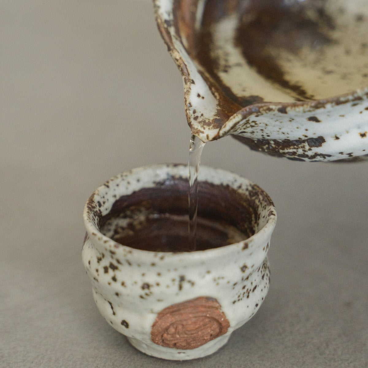 Nahaufnahme der weißen japanischen Sake-Karaffe Zui und Ochoko-Tassen auf einer Holzoberfläche, die dem Raum zeitlose Eleganz verleiht