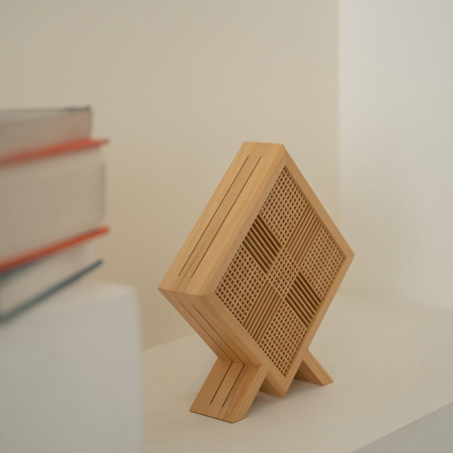 "Gros plan d'une lampe de table japonaise en bois non allumée « Kanata » révélant un travail du bois Kumiko fin et sa forme unique en losange sur une console de style Japandi."
