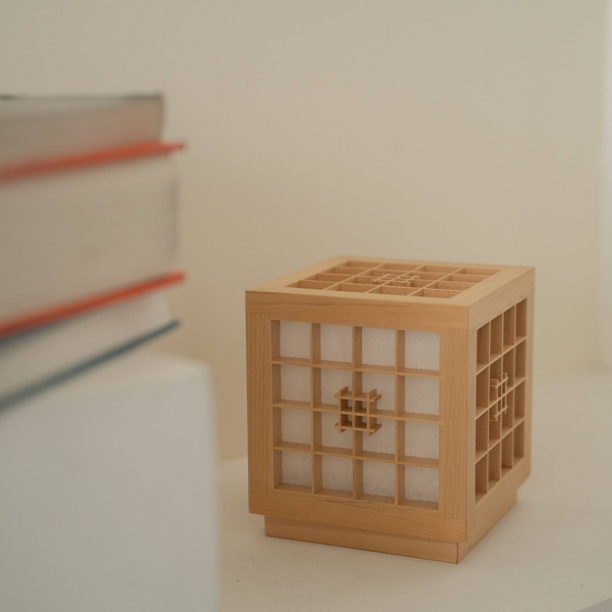 "Lampe de table japonaise en bois « Honoka » avec un travail détaillé du bois Kumiko à côté de livres comme accent décoratif fait à la main."