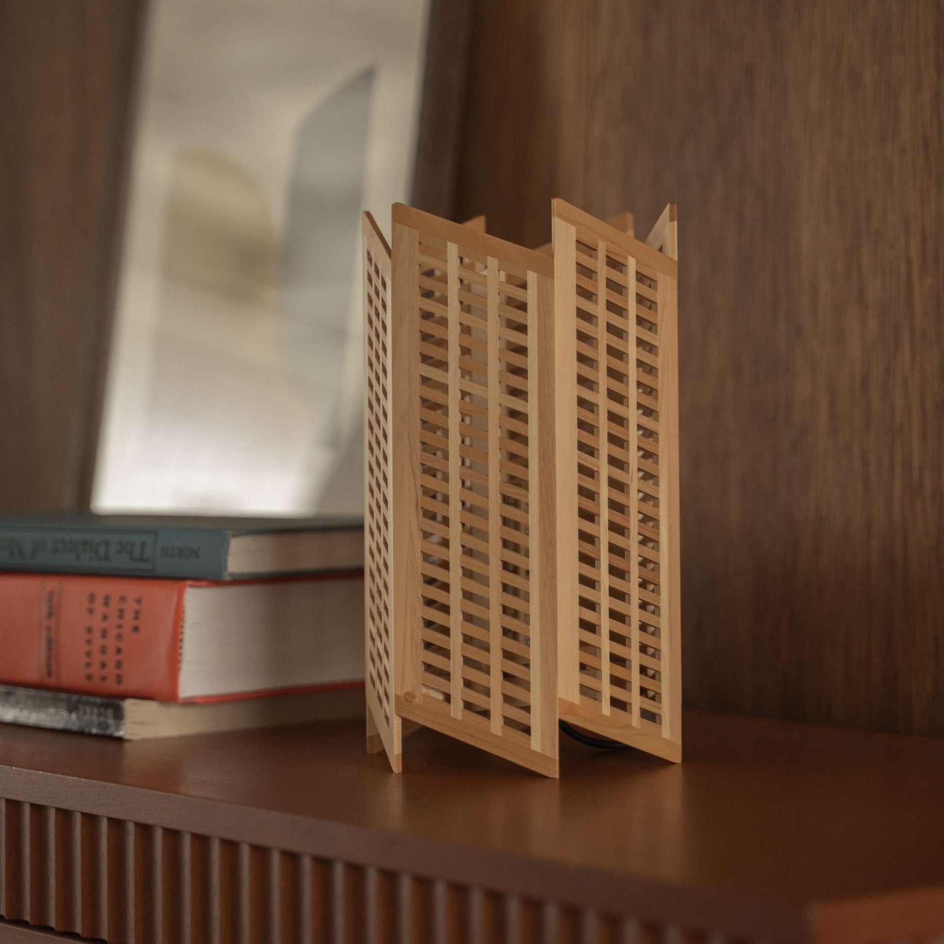 Gros plan d'une lampe de table japonaise en bois "Towaru" révélant un travail du bois kumiko précis sur une console, comme décoration wabi sabi.