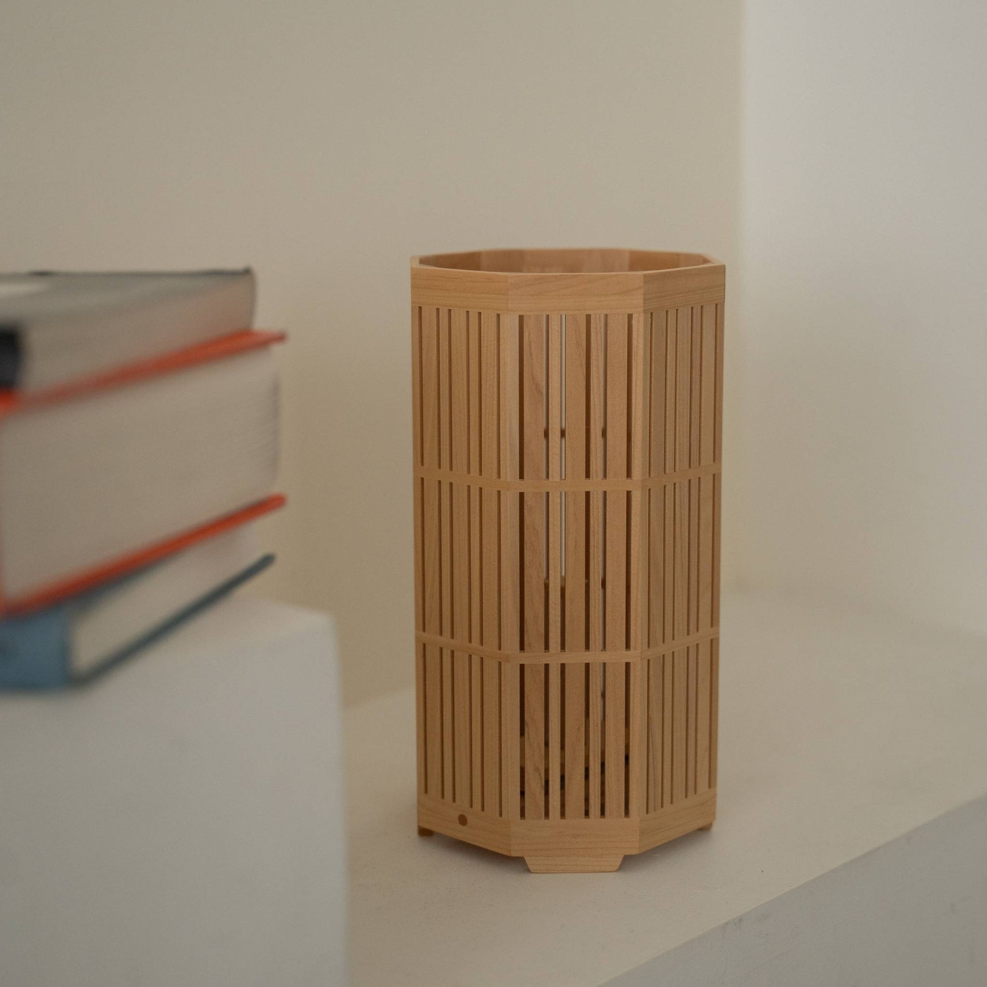 Gros plan d'une lampe de table japonaise en bois "Kagayaki" mettant en valeur un travail du bois Kumiko détaillé sur la console blanche dans une pièce de style Japandi.
