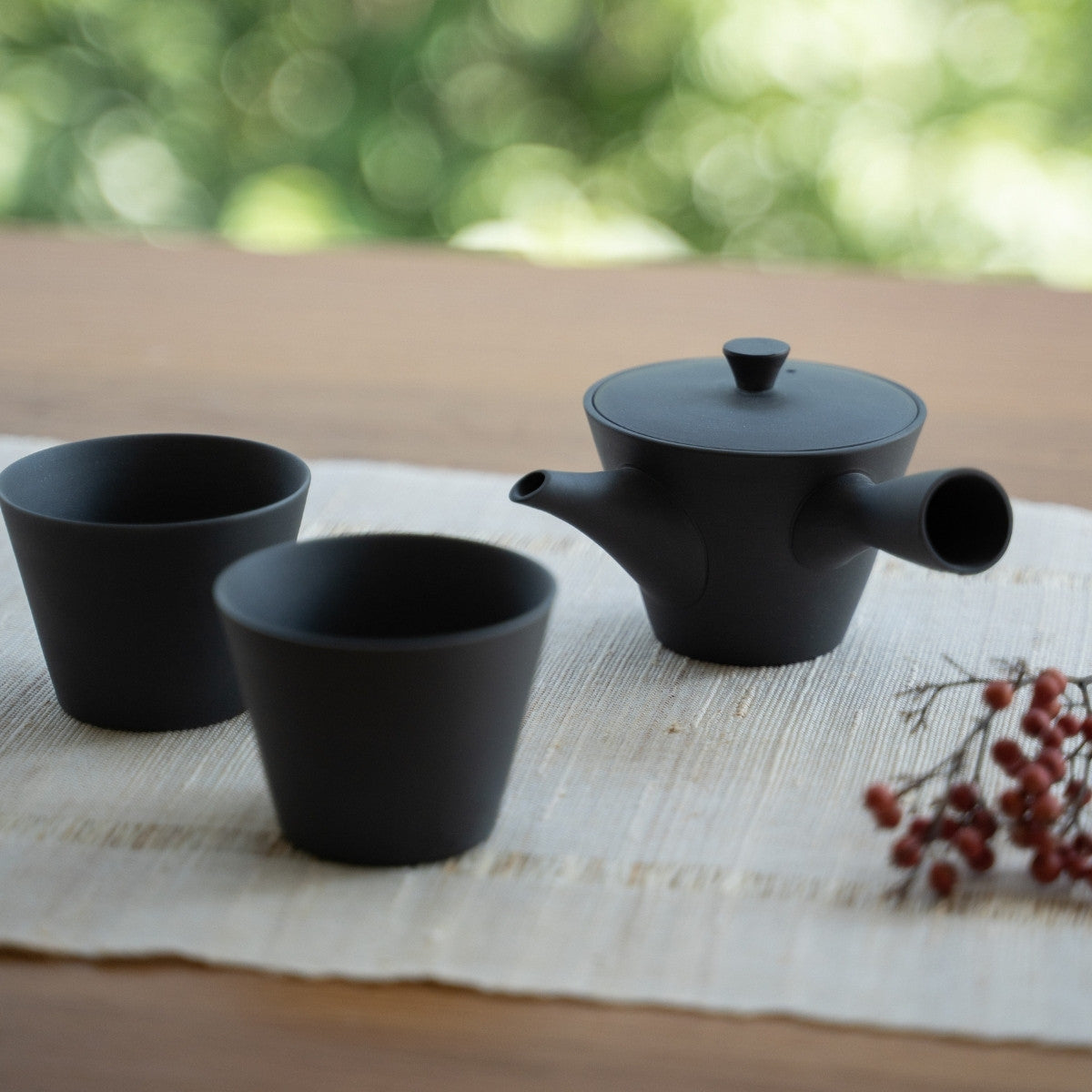 Black Japanese teapot "Sencha" and Japanese tea cups on a table for tea lovers savoring a modern zen moment.