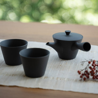 Black Japanese teapot "Sencha" and Japanese tea cups on a table for tea lovers savoring a modern zen moment.