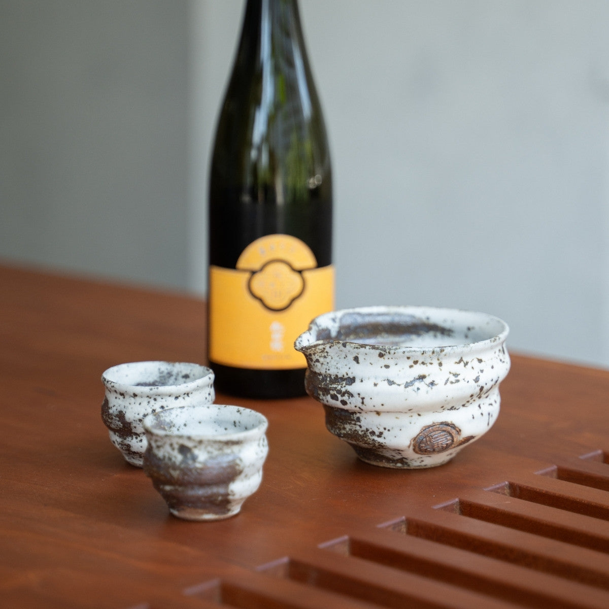 Ensemble de saké japonais blanc Zui irrégulier, carafe et tasses sur une table à manger, pour apporter de l'élégance aux dîners spéciaux avec des invités