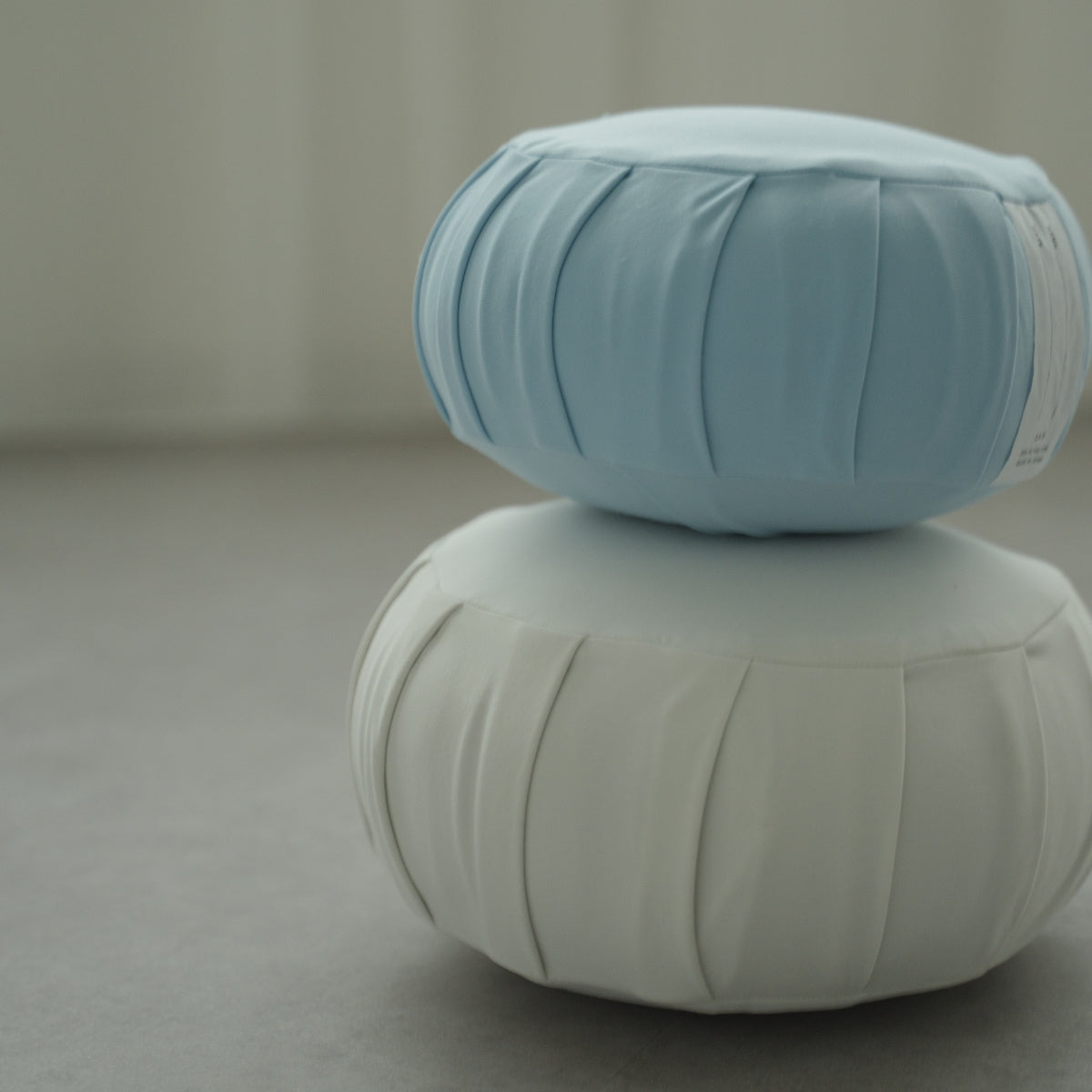 Calm blue and moonlight white Japanese meditation cushion zafu, stacked on a modern floor for relaxing family yoga.