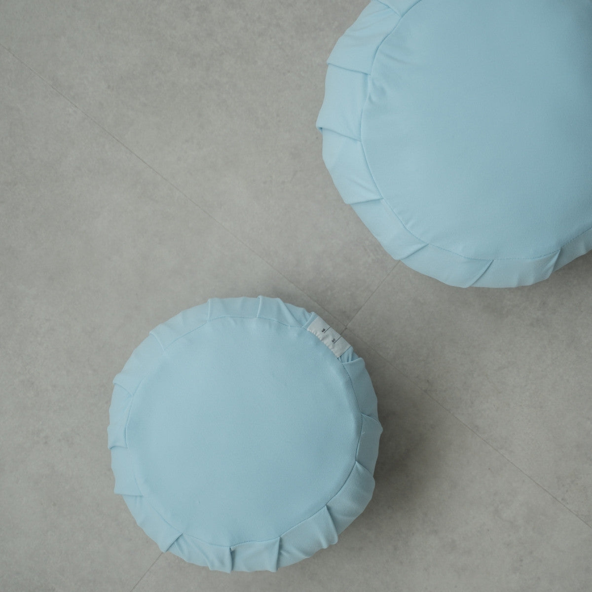 Two calm blue Japanese meditation cushions (zafu), on a modern grey floor, arranged for a shared family zen practice.