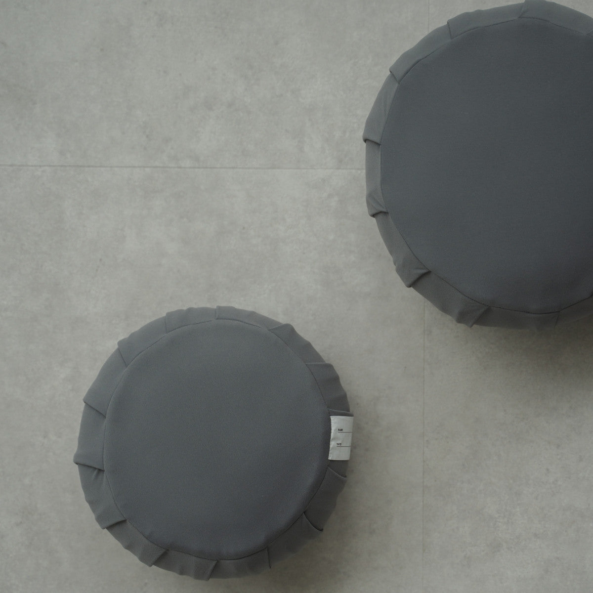 Two charcoal grey Japanese meditation cushions (zafu) on a modern floor, arranged for a shared family zen routine.