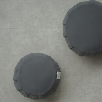 Two charcoal grey Japanese meditation cushions (zafu) on a modern floor, arranged for a shared family zen routine.