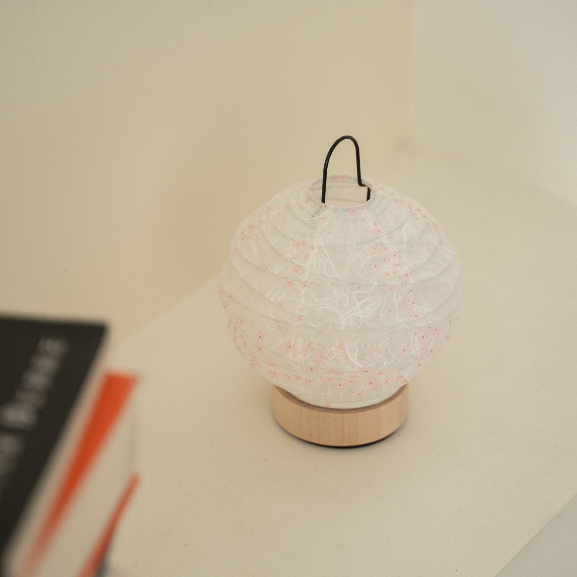 Close-up of an unlit round Japanese paper table lamp "Yuhi" Sakura showcasing its textured paper surface for wabi sabi decor on a Japandi living room console table.