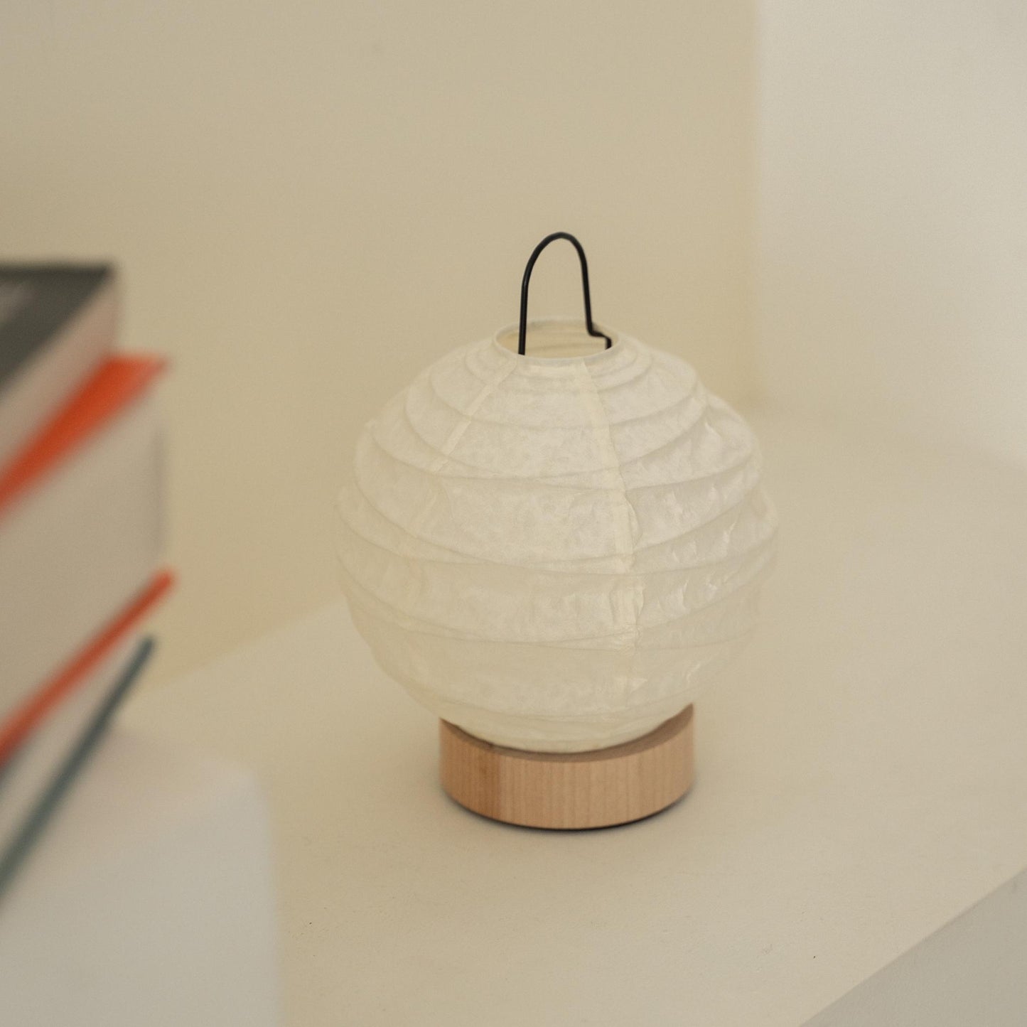 Close-up of an unlit round Japanese paper table lamp "Yuhi" showcasing its textured paper surface for wabi sabi decor on a Japandi living room console table.