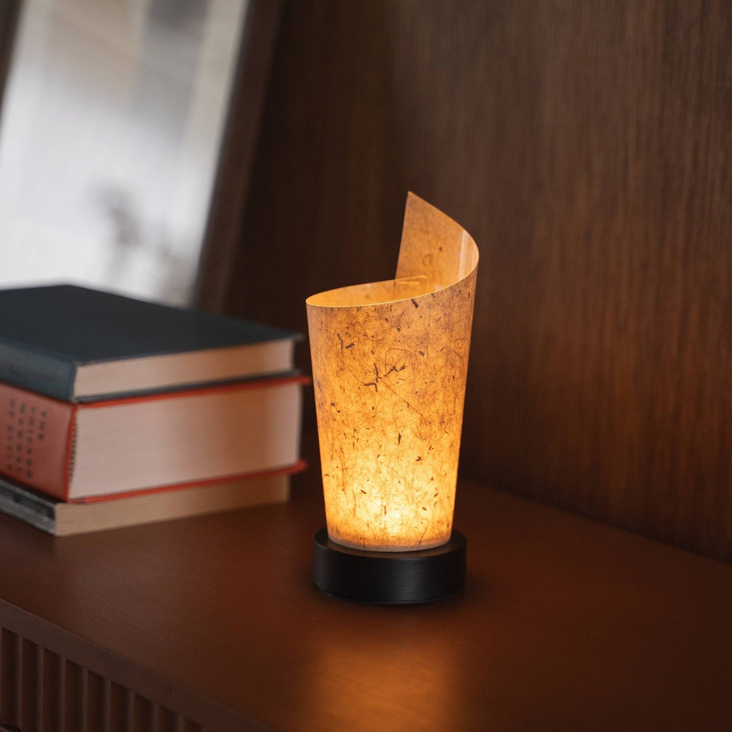 Close-up of a lit Japanese paper table lamp "Maki" Cedar Bark serving as a warm accent lamp with delicate paper texture and a wood base.