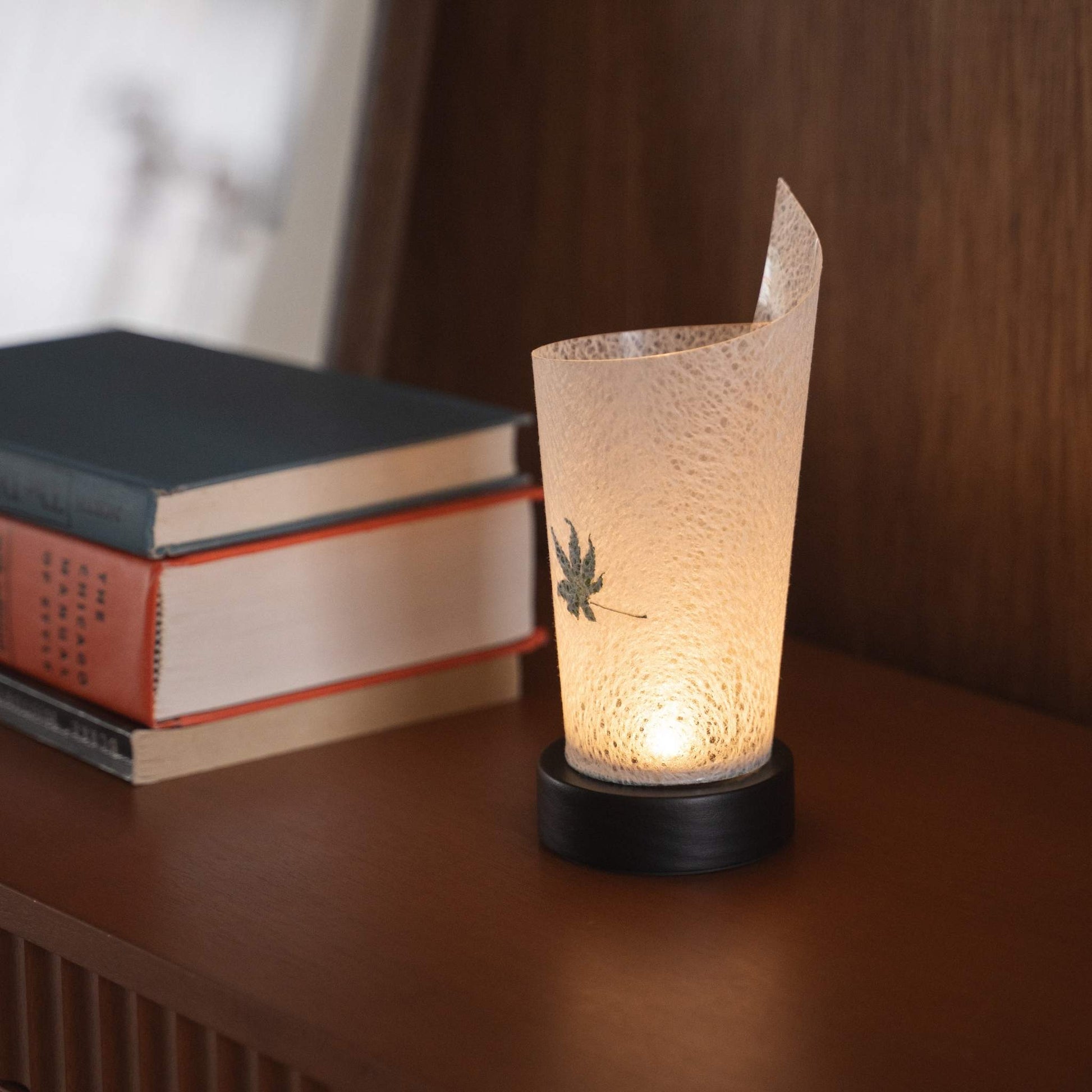 Close-up of a lit Japanese paper table lamp "Maki" Momiji Leaf serving as a warm accent lamp with delicate paper texture and a wood base.