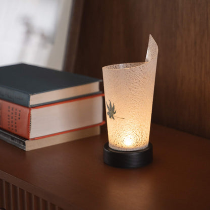 Close-up of a lit Japanese paper table lamp "Maki" Momiji Leaf serving as a warm accent lamp with delicate paper texture and a wood base.
