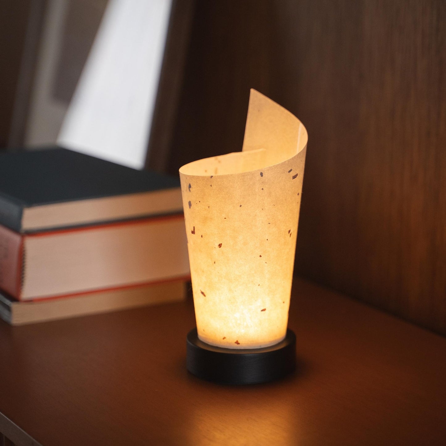Close-up of a lit Japanese paper table lamp "Maki" serving as a warm accent lamp with delicate paper texture and a wood base.