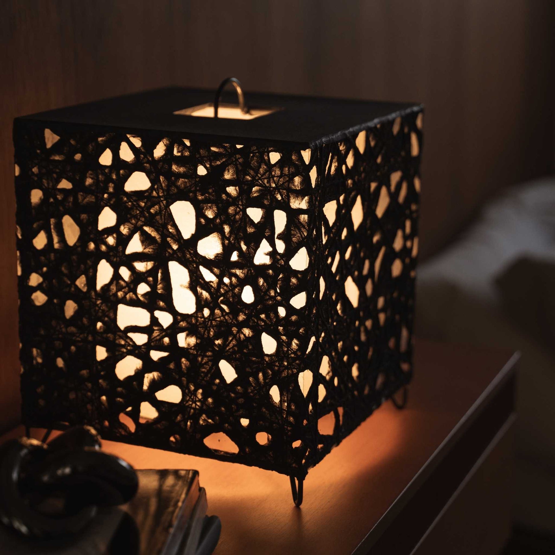 Close up of the illuminated Me-Look 03 lamp shade showing the intricate black fiber texture and soft warm light.