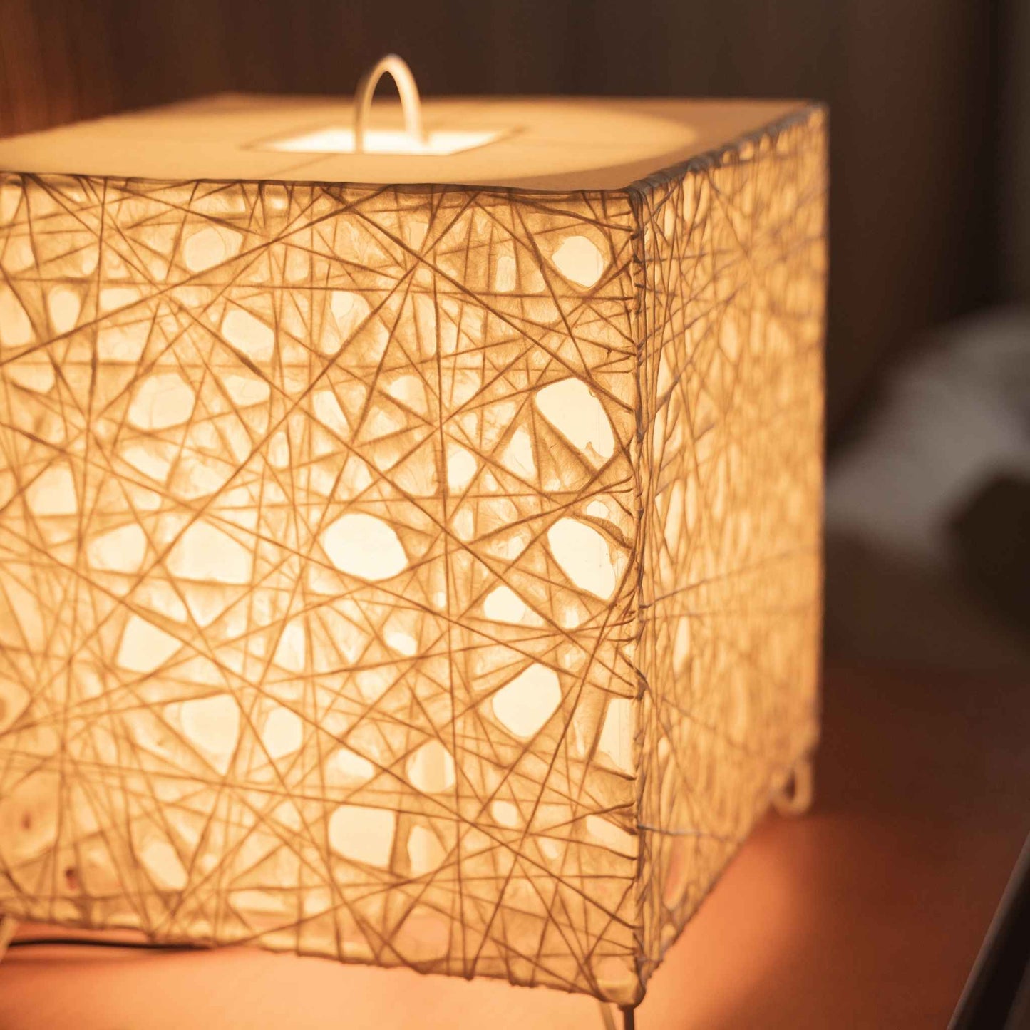 Close up of the illuminated Me-Look 03 lamp shade showing the intricate white fiber texture and soft warm light.