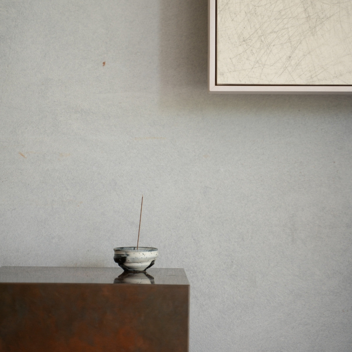 Cloud white Japanese incense burner with a lit stick on a dark wooden console, adding a wabi-sabi touch to a living room.
