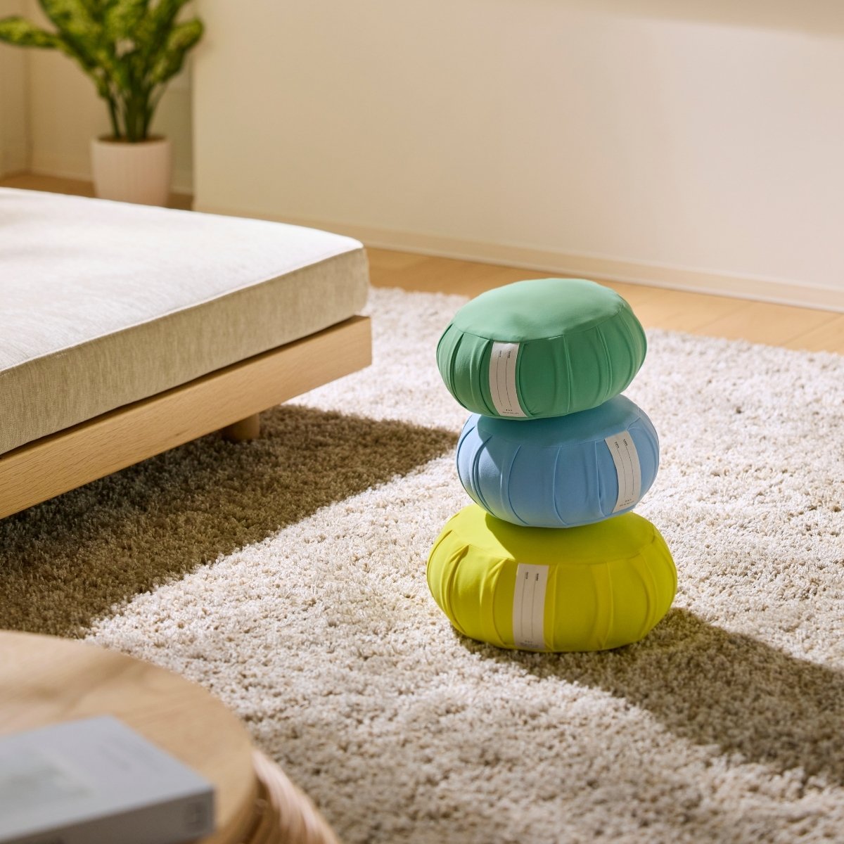 Mint green, calm blue, and mimosa yellow Japanese meditation cushion zafu stacked on a rug for a family zen routine.